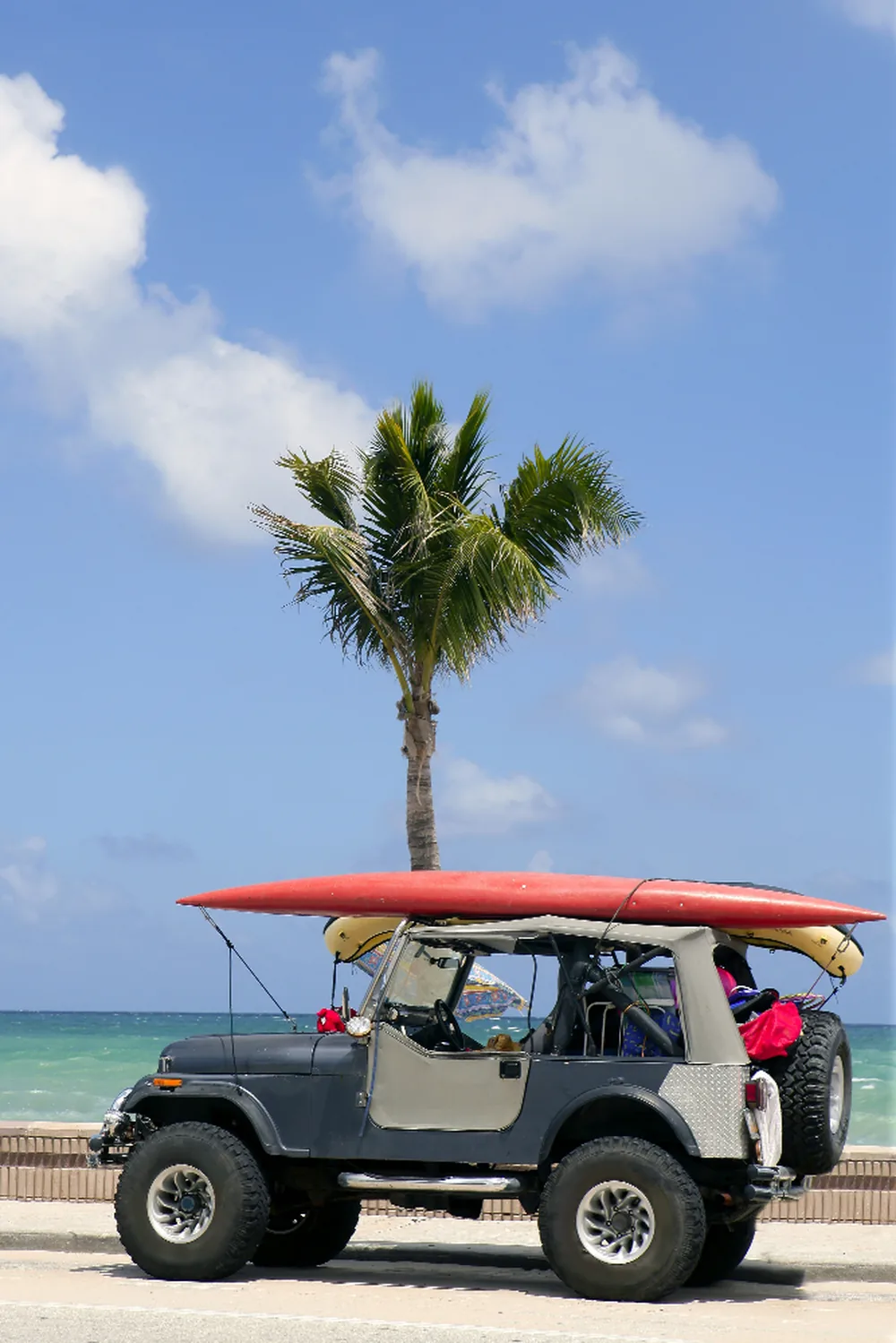 Open-air Jeep with surfboards parked on a Bahamas Out Island beach